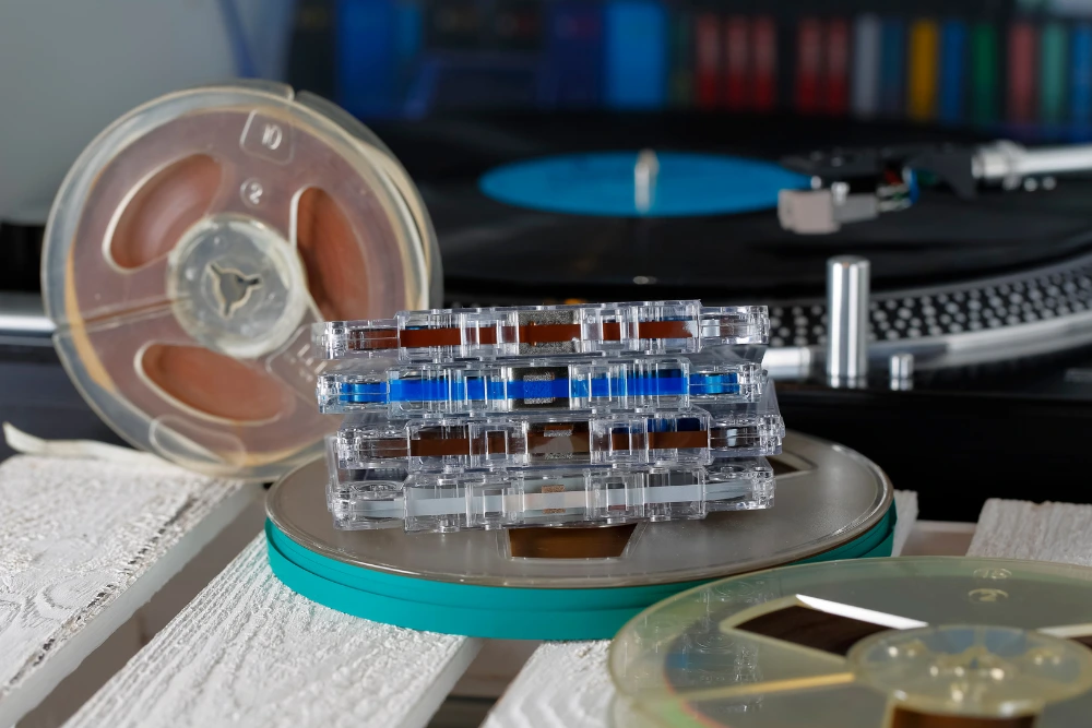 Reel-to-reel tapes and cassettes stacked in front of a turntable